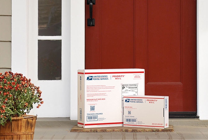 Priority Mail boxes on a house porch awaiting pickup.